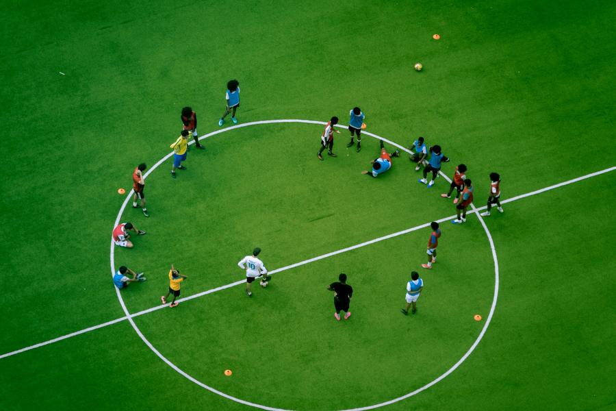 Yukarıdan çekilmiş, orta yuvarlakta antrenman yapan genç futbolcular