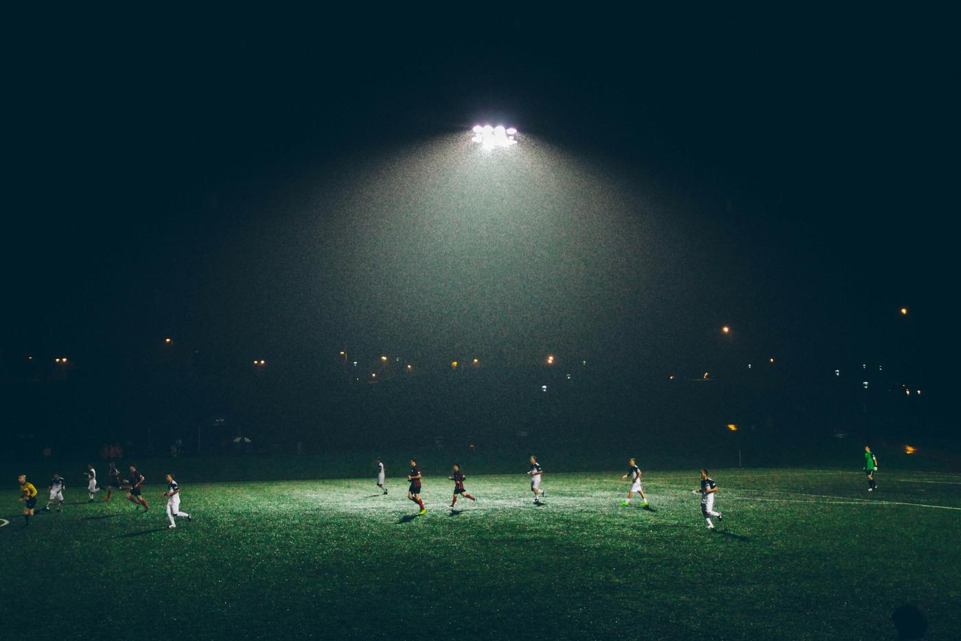 Gece, tek bir projektörün aydınlattığı sahada maç oynayan futbolcular