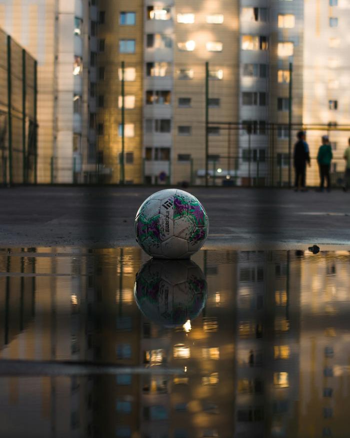 Islak zeminde, apartman ışıklarının yansıdığı bir futbol topu